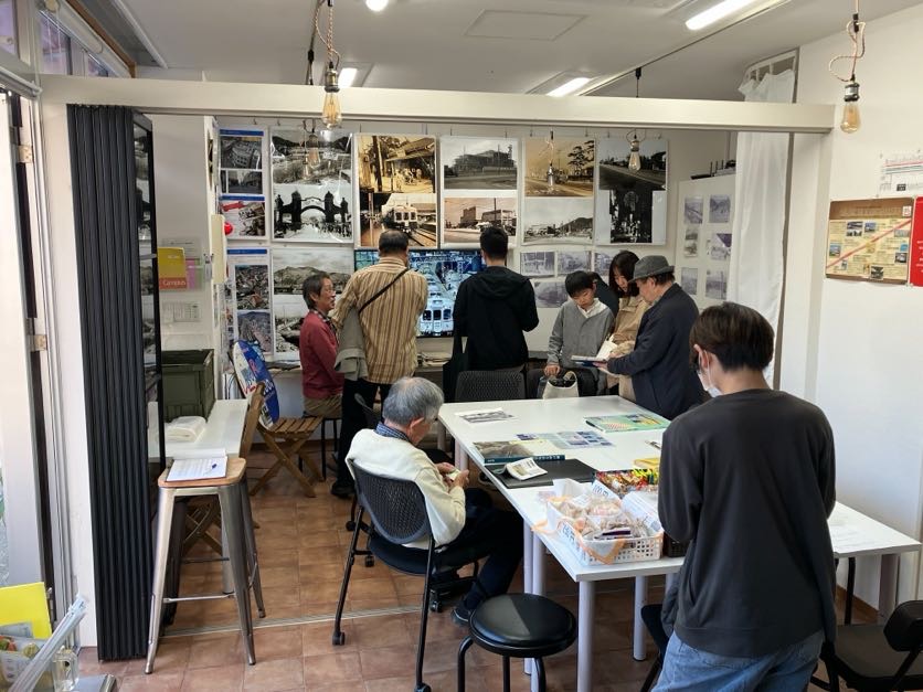 写真展「懐かしの月見山駅ものがたり～夢とロマンを運ぶ山陽電車～」モノクロ写真を中心に、好き深山界隈を中心とした須磨区の海沿いの町風景写真や、かつて須磨の町を走った蒸気機関車や路面電車山陽電車の写真げ壁にぎっしりと展示され、山陽電車様からお借りしたヘッドマークが並び、モニターには懐かしい写真のスライドショーを上映。イベント会場に年齢や性別問わず、多くの来場者さまでにぎわう様子。