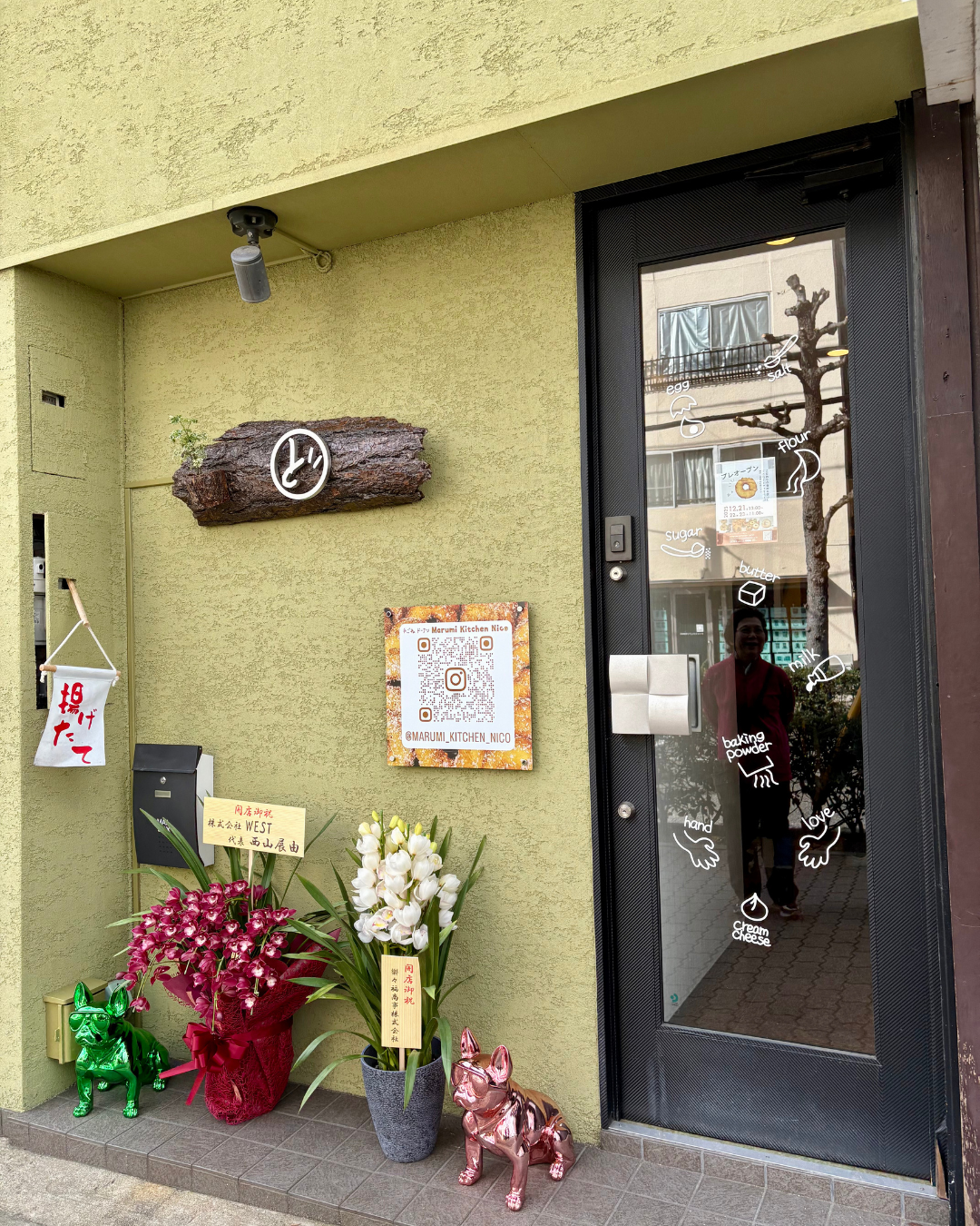 月見山エリアにmarumi kitchen donutさんがオープン・黄緑色の外壁、黒いドアのガラスにはかわいいドーナツのイラストが描かれ、お祝いのお花がたくさん並んでいました